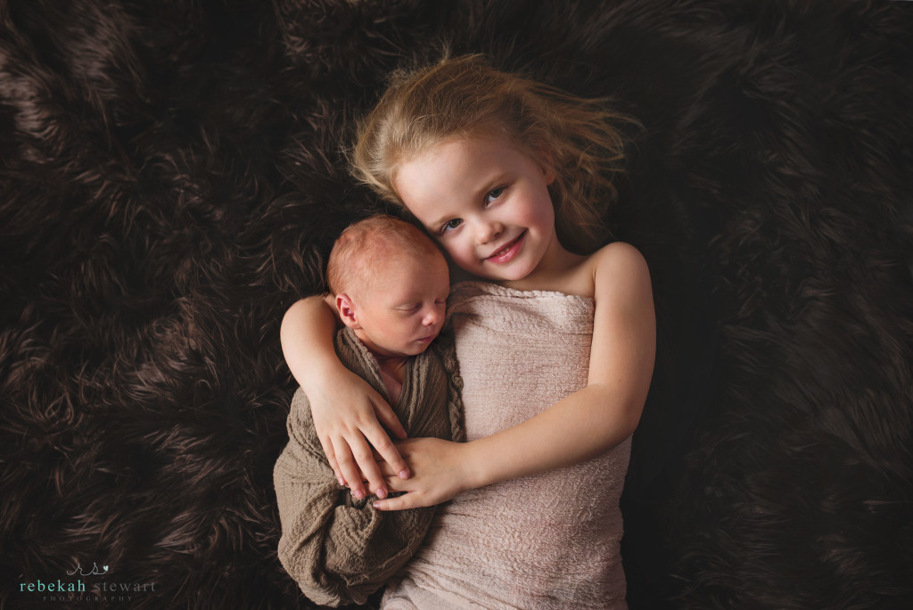 A big sister snuggles her newborn baby brother in Iowa City