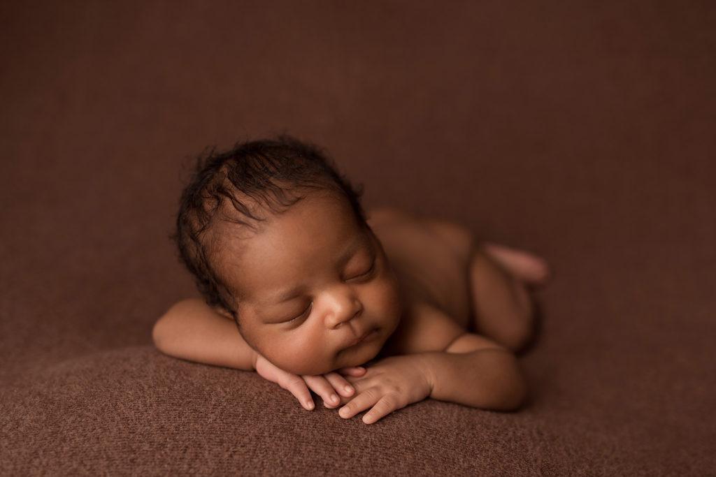 A baby boy sleeps on a brown blanket during his session with newborn photographer in Cedar Rapids