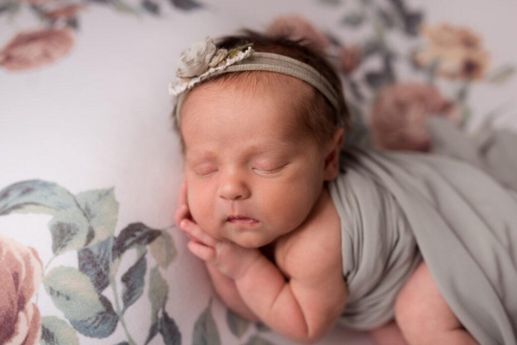 A baby girl sleeps on a floral blanket during her newborn photos in Cedar Rapids Iowa City - staying active during pregnancy