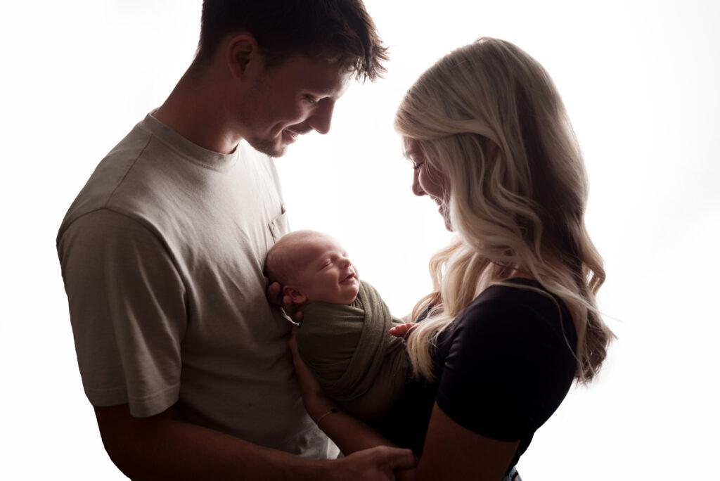 A gorgeous couple snuggles their newborn baby boy during their photography session in cedar rapids ; choosing an OB