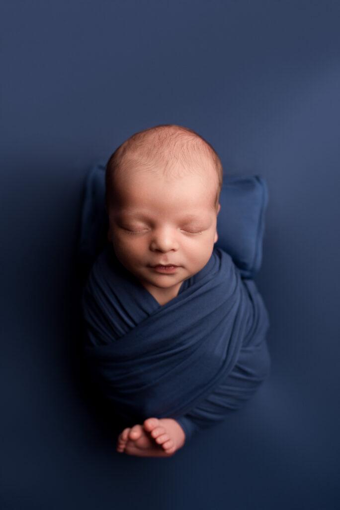 A baby boy sleeps during his newborn photos in Cedar Rapids Iowa