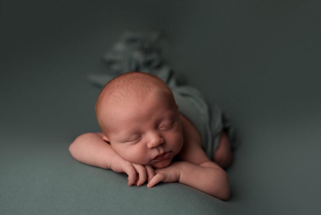 A newborn baby boy sleeps during his photography session in Cedar Rapids