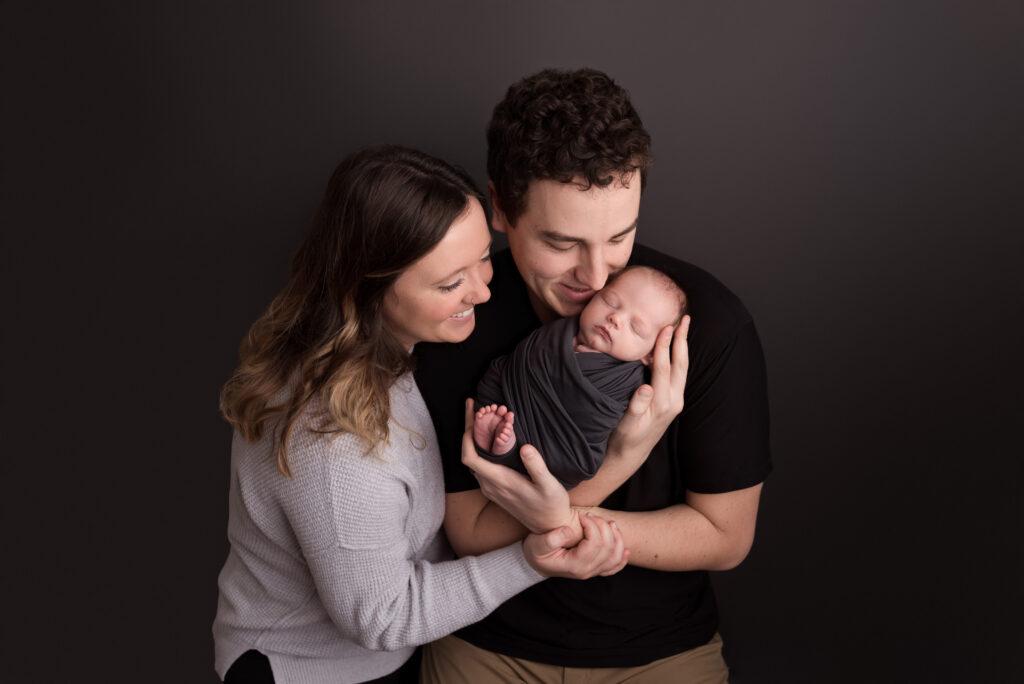 A gorgeous couple snuggles their new baby boy during their newborn photos in Cedar Rapids